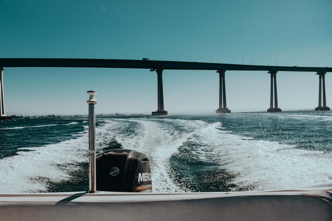 A scenic view from a boat ride underneath a large coastal bridge with a clear blue sky.
