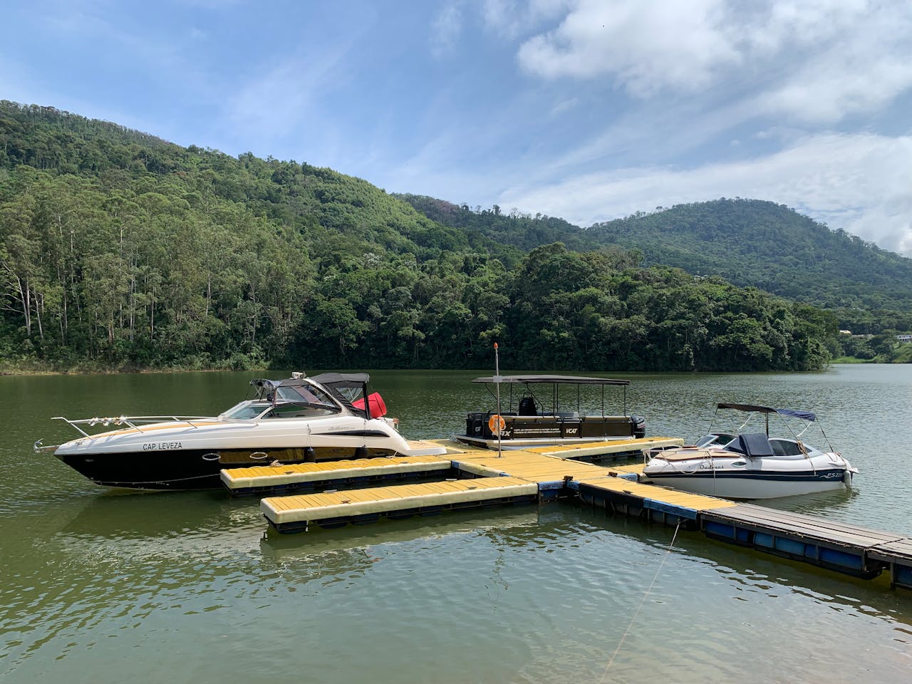 contact-header Boats docked on a lake surrounded by lush green hills and sunny skies, offering a peaceful getaway.