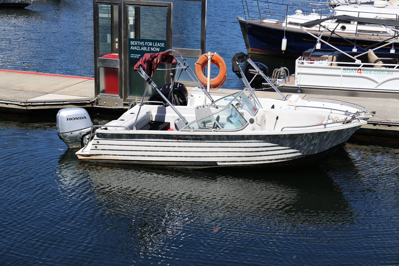 A motorboat with a Honda engine docked at a marina under bright sunlight.