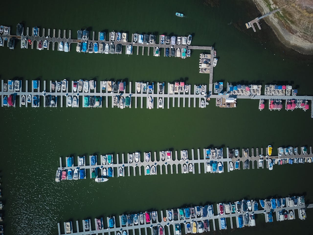 about-002 Top-down aerial view of numerous boats docked at a marina with lush green water.